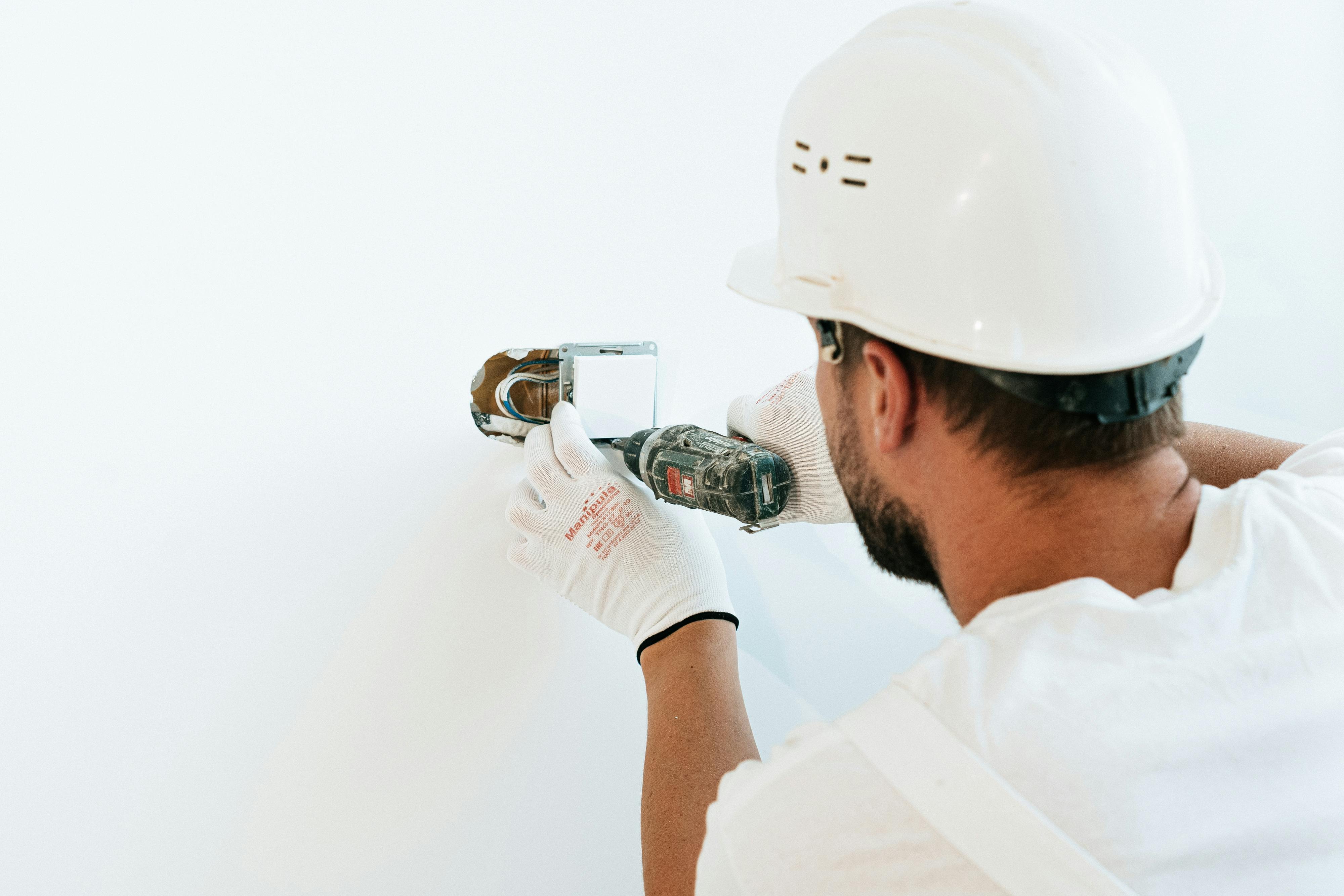 Ouvrier avec casque blanc installant une prise électrique sur un chantier